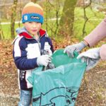 Ein Junge und eine Frau sammeln Müll.