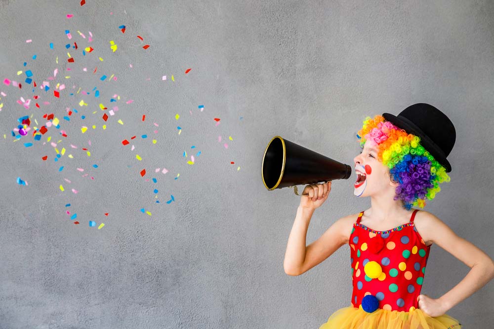 Kind als Clown verkleidet mit Megaphon in der Hand.