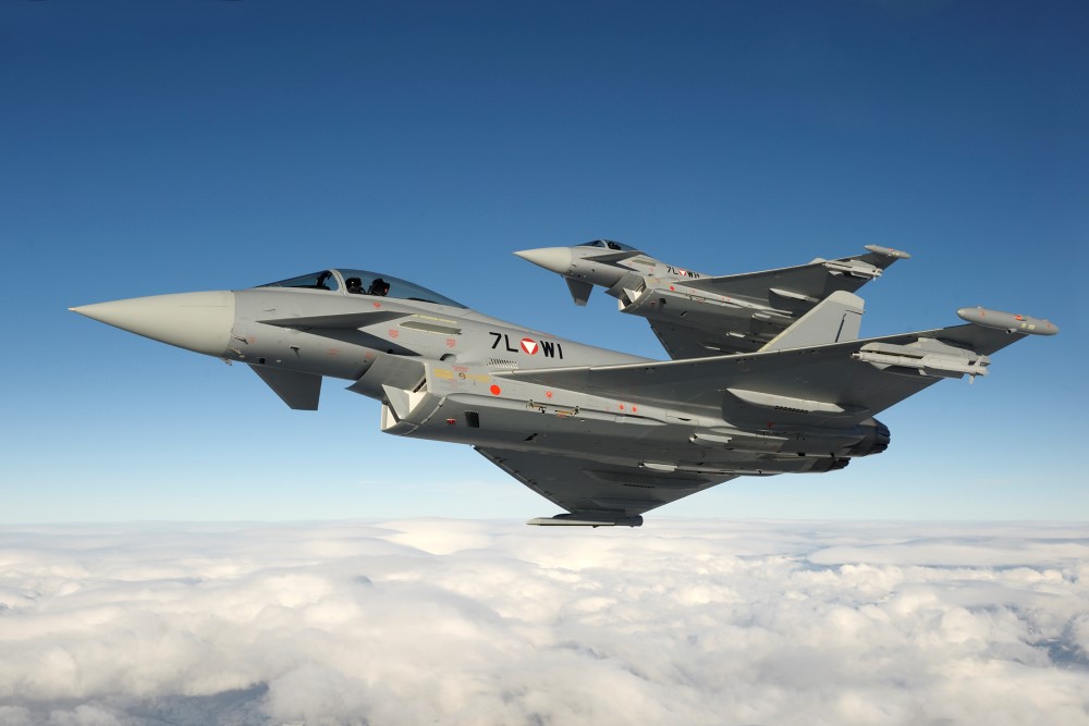 Zwei Eurofighter über grau-weißen Wolken vor blauem Himmel