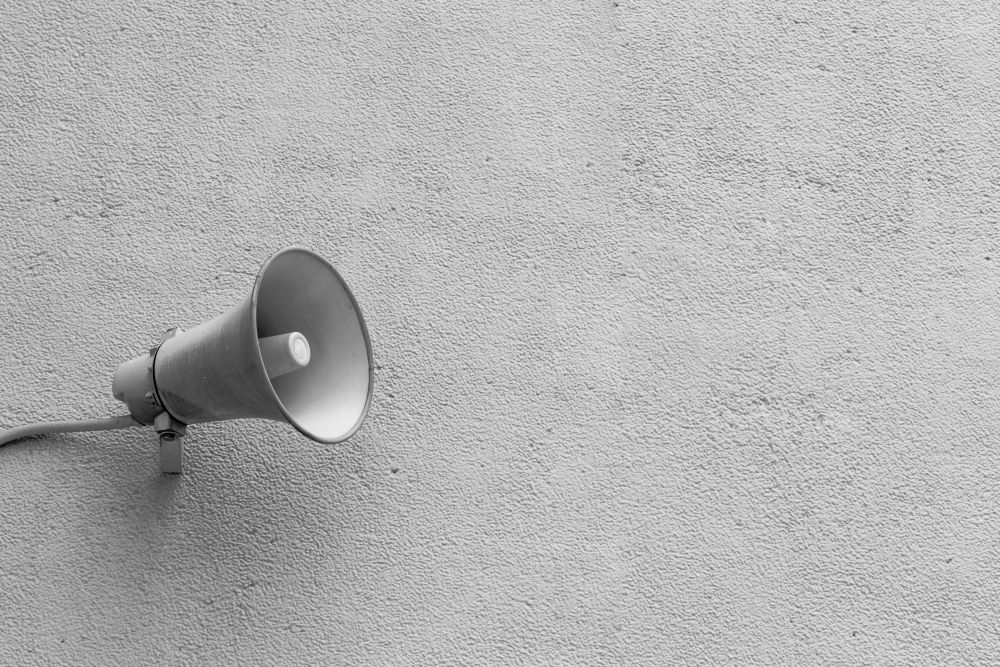 An einer grauen Betonwand ist ein grauer Lautsprecher montiert, die Öffnung zeigt nach rechts. AM ersten Samstag im Oktober findet jährlich die Sirenenprobe statt, im Rahmen des Zivilschutztages.