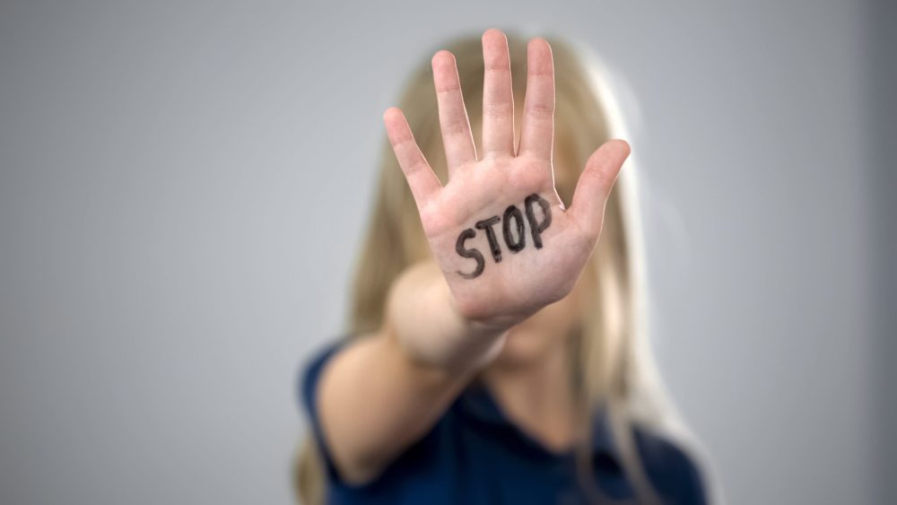 Beitragsbild Selbstverteidigungskurs zeigt ein Mädchen das die Hand hochhält. In ihrer Handfläche steht STOP in schwarzen Buchstaben.